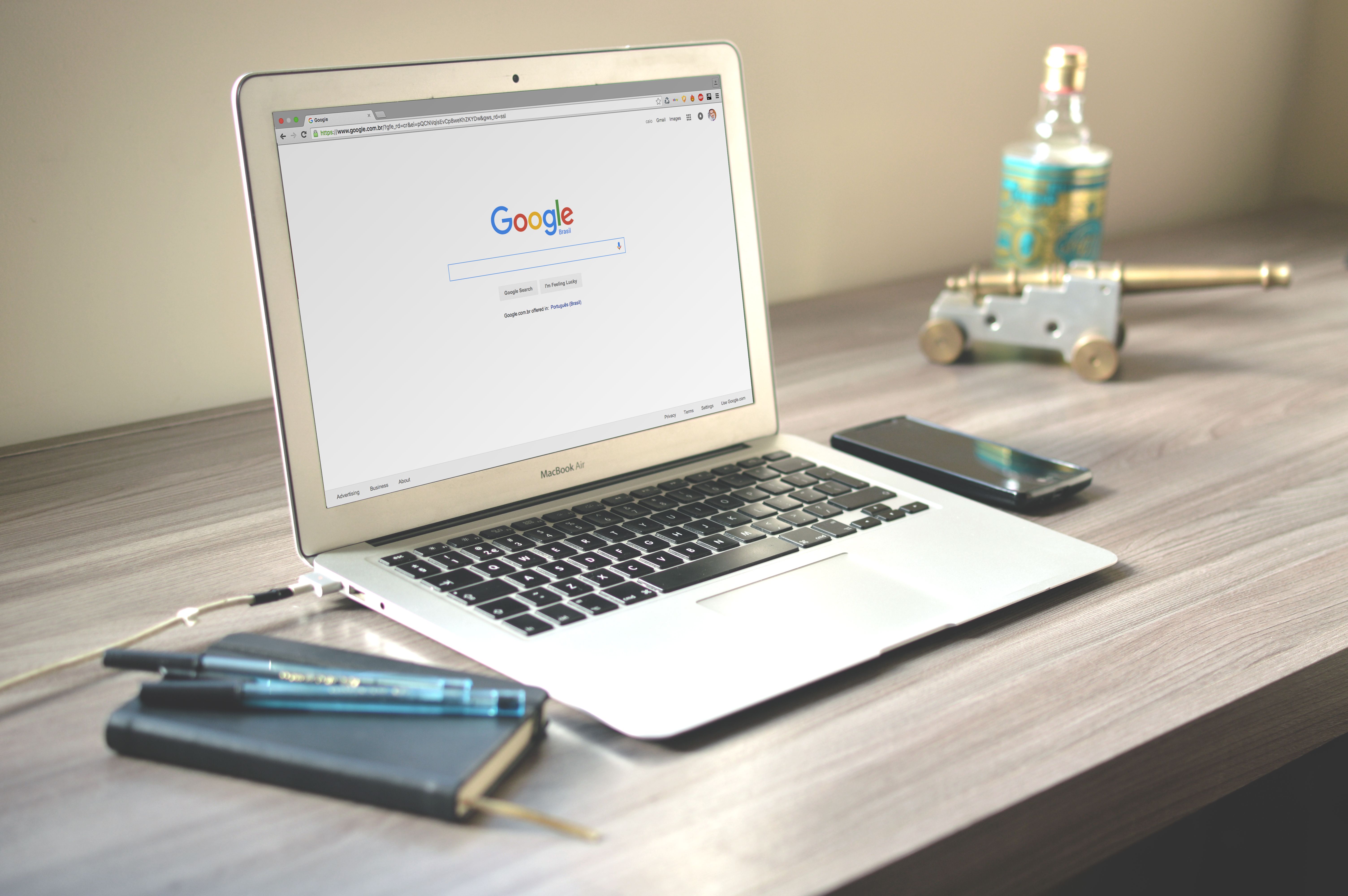 Workspace with a laptop showing Google search, smartphone and notebook