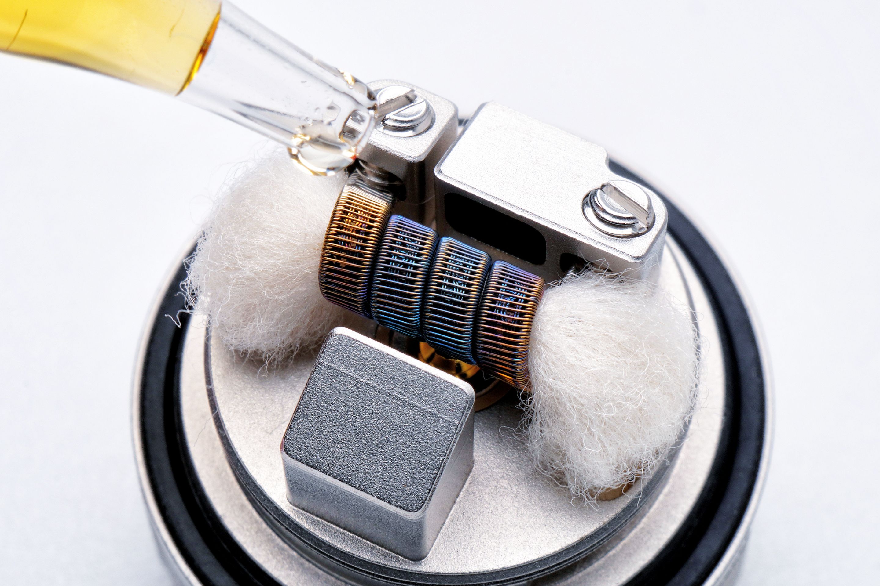 Macro shot of a vape heating coil being primed, showing hardware technology and craftsmanship