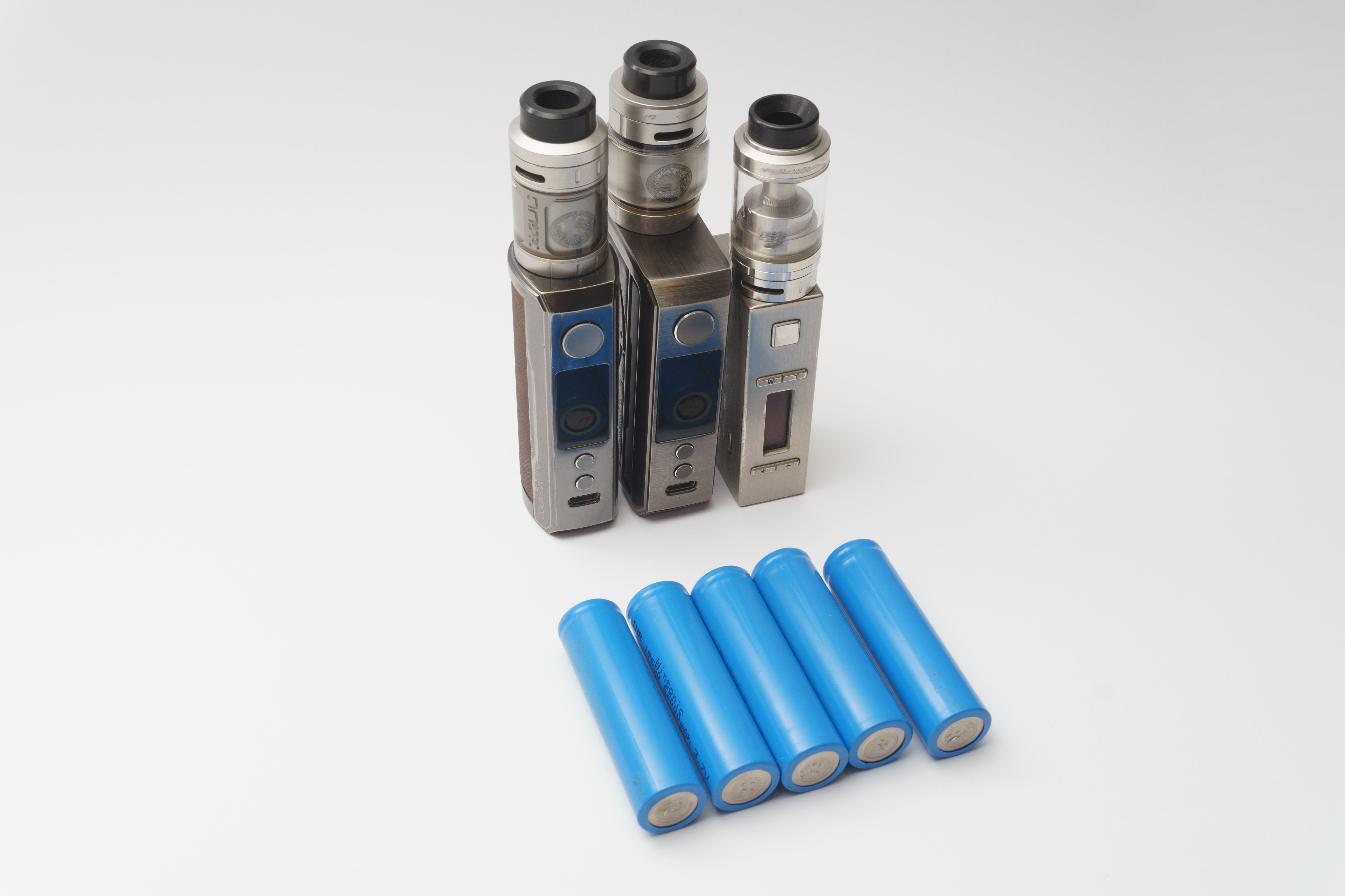 Three vape mods with six 18650 batteries arranged on a white surface