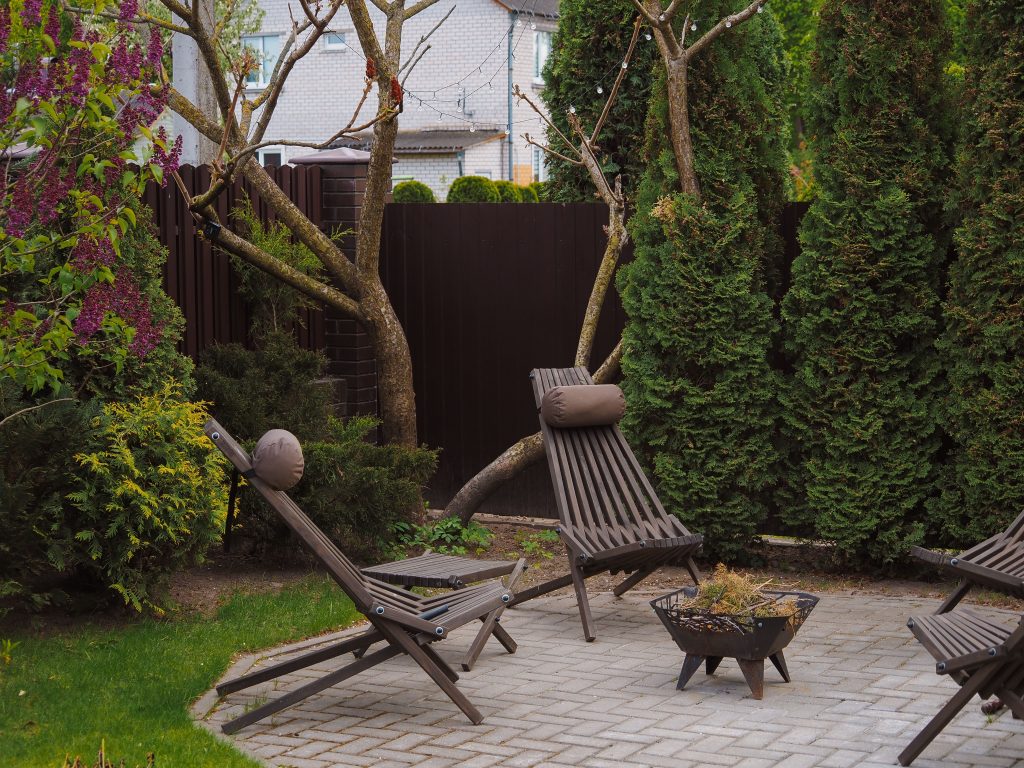 Cozy backyard with wooden lounge chairs and lush greenery, illustrating a simple outdoor seating upgrade.