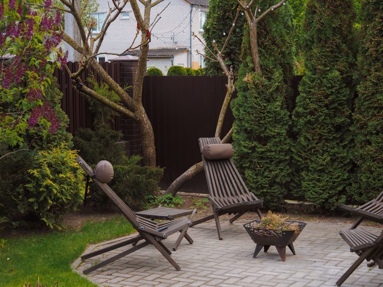 Cozy backyard with wooden lounge chairs and lush greenery, illustrating a simple outdoor seating upgrade.